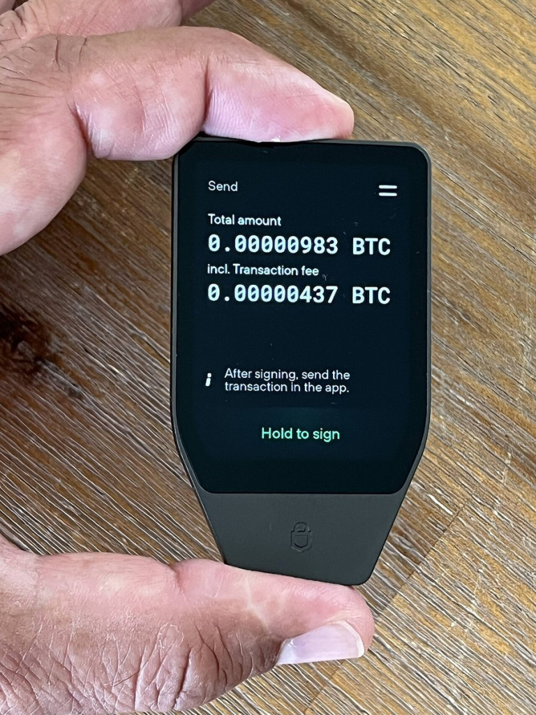 硬件钱包第一次设置：把设备确认放在最前面｜主题资料图：A Trezor Safe 7 cryptocurrency hardware wallet displaying this Bitcoin transaction. This d